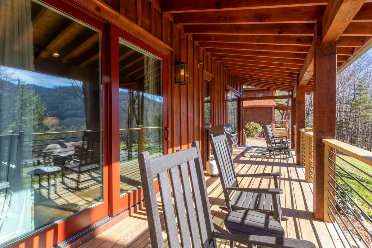 A classic porch scene with wooden rocking chairs positioned to take in expansive mountain views, framed by a sturdy deck railing. The setting exudes calm, inviting moments of morning coffee or sunset-watching in a peaceful environment.
